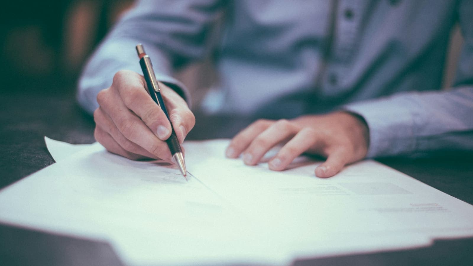 A man signing a document at a desk