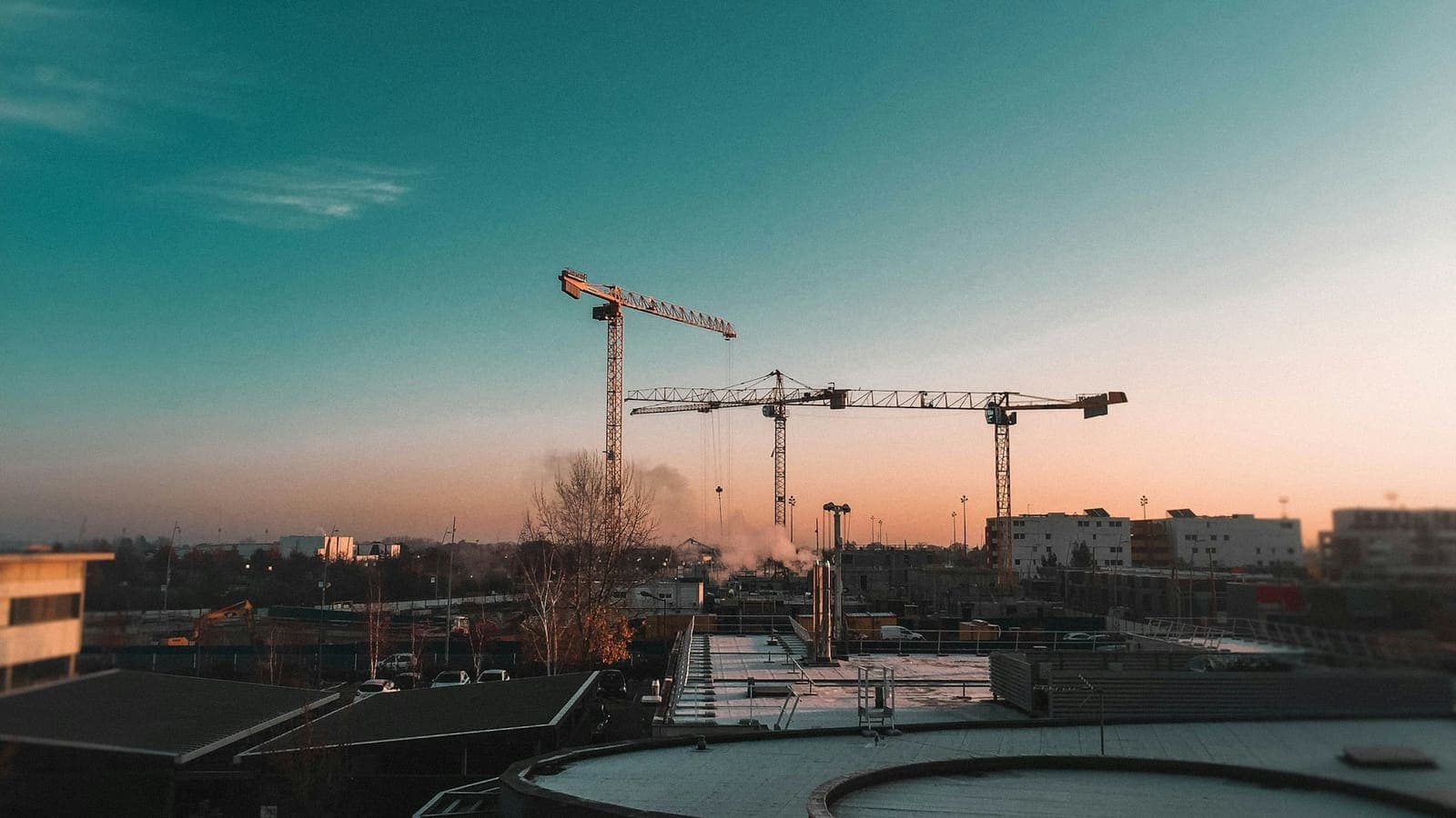 Des grues à tour dominant des immeubles en construction sous un ciel bleu