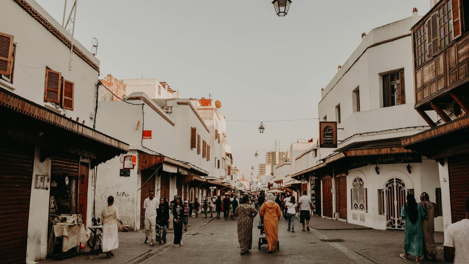 أشخاص يسيرون في شارع مدينة بجانب مبانٍ شاهقة