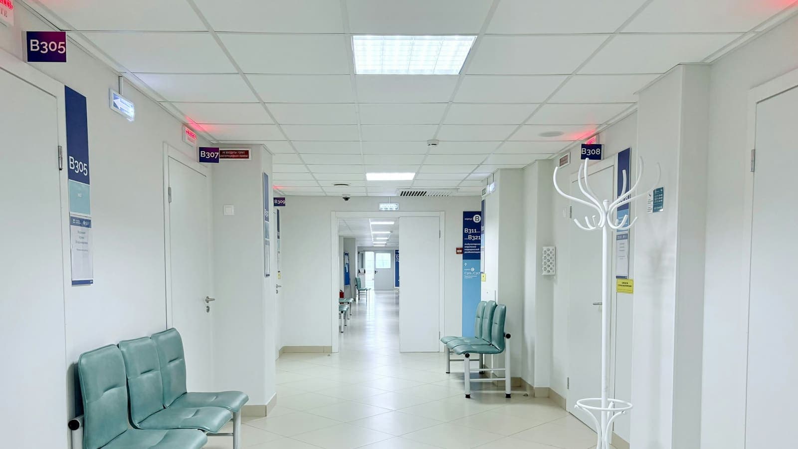 An empty hospital corridor with benches and doors