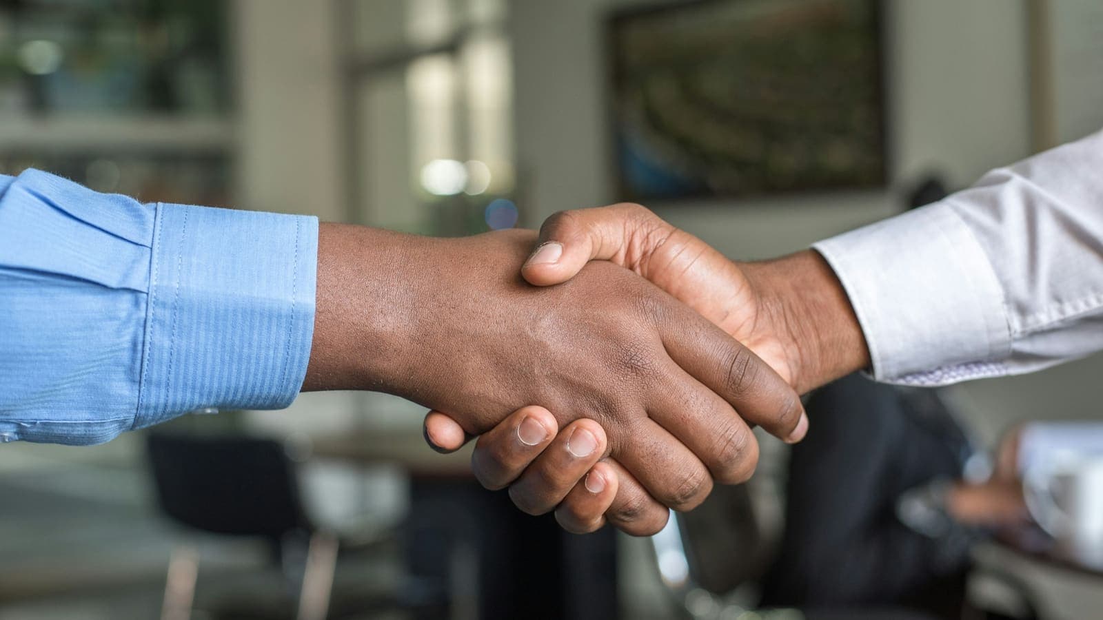 Two people shaking hands to close a deal, photographed against a dark background