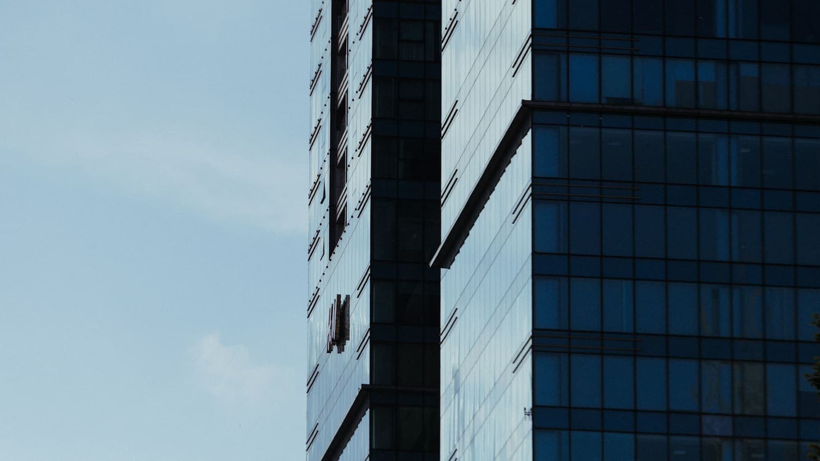 A modern glass office tower against a clear blue sky