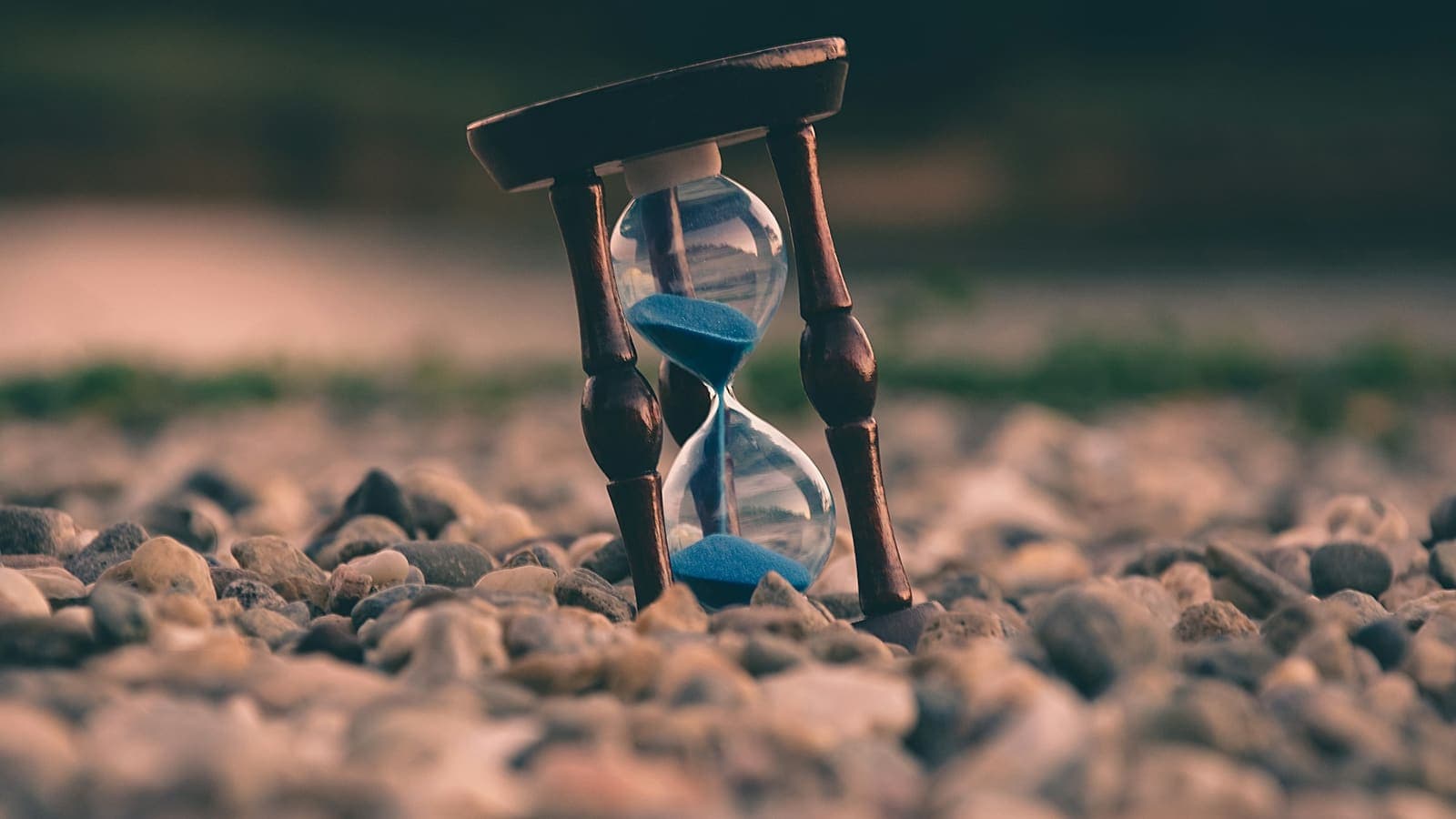 An hourglass resting on stones with the sand running out