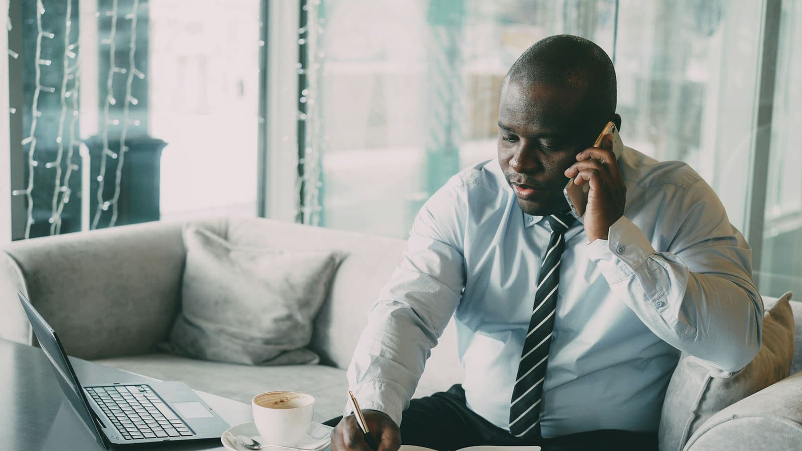 A man in a shirt and tie making a phone call at his desk — senior time spent on outreach