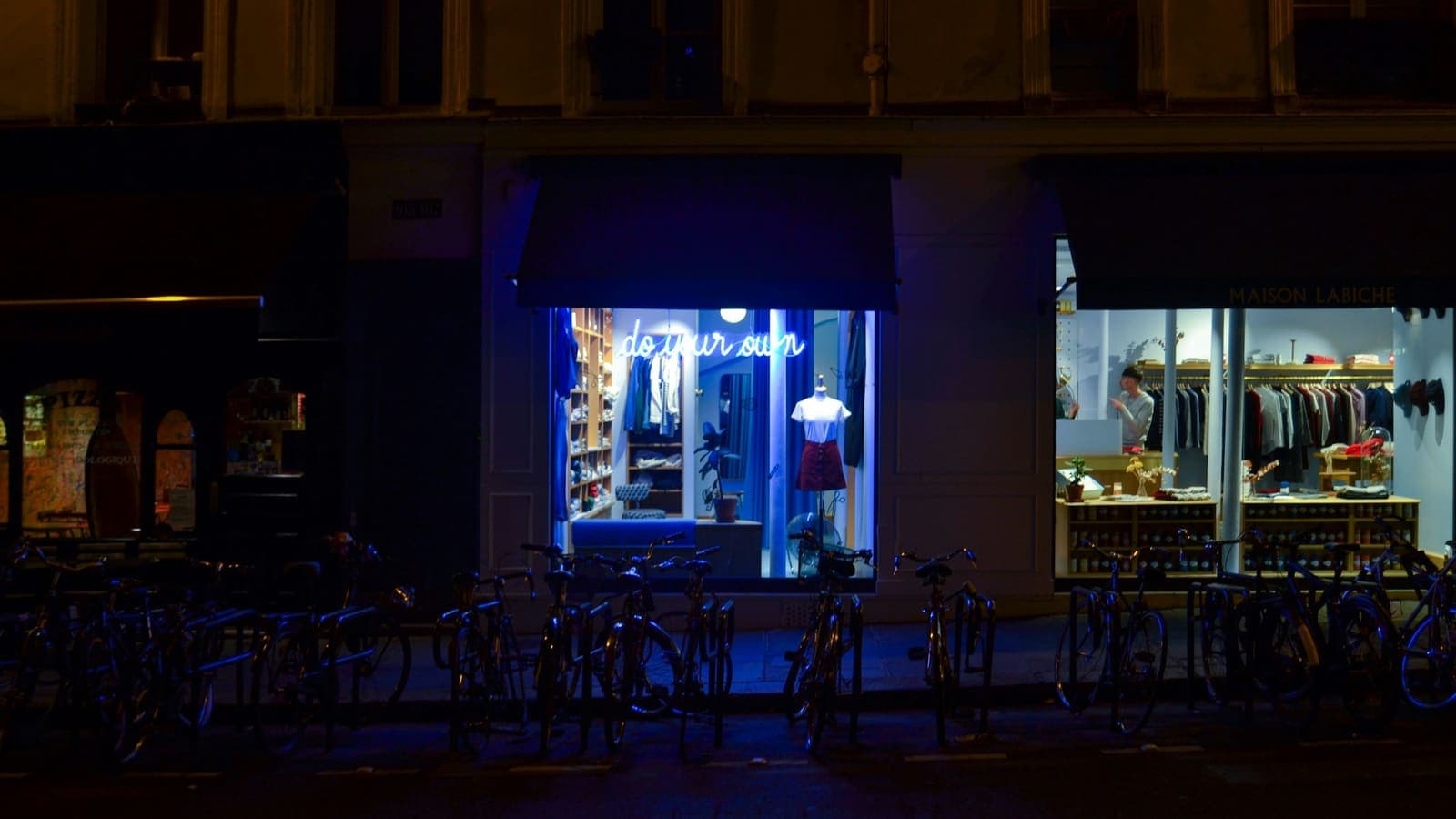 Une petite boutique éclairée la nuit dans une rue de ville